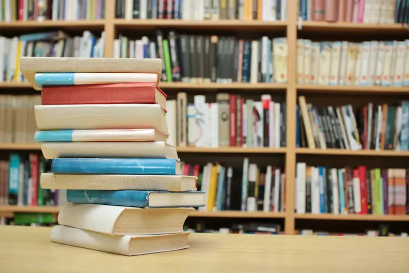 Stack of multi-colored books on a table in a library.
