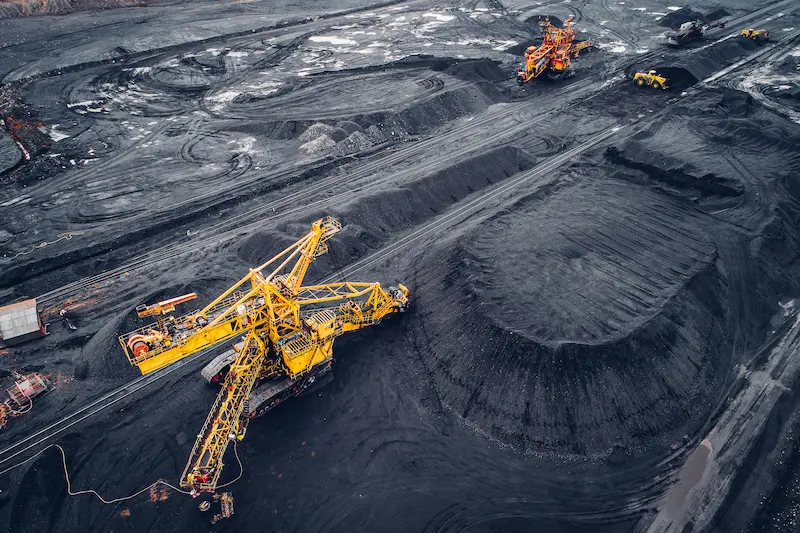 Large yellow excavators mining coal from an open pit.
