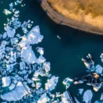 Aerial photo of an iceberg floating in a glacial lagoon.