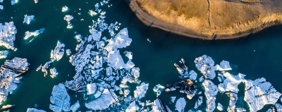 Aerial photo of an iceberg floating in a glacial lagoon.