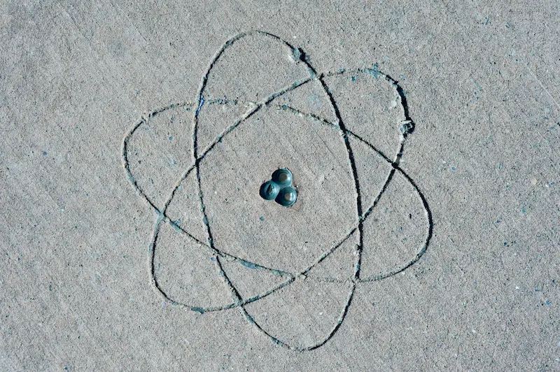 Atomic symbol with electron orbitals surrounding a nucleus etched into a concrete surface.