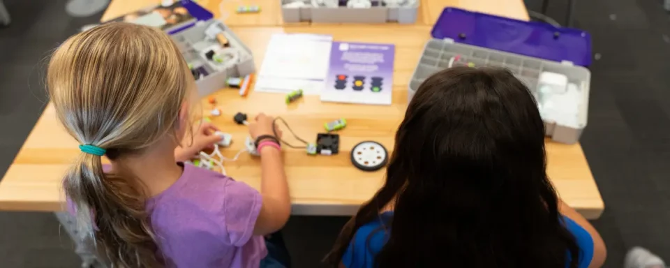 Two girls building a small robot car.
