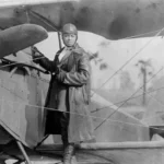 Black and white photo of Bessie Coleman in front of her airplane.