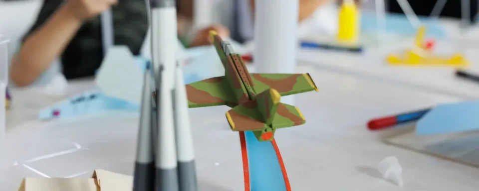 A painted model airplane next to a model rocket ship on a table.