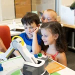 Student celebrating after completing a task with a robotic arm in a STEM classroom.
