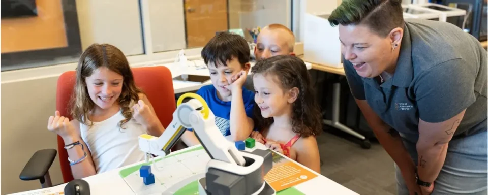 Student celebrating after completing a task with a robotic arm in a STEM classroom.