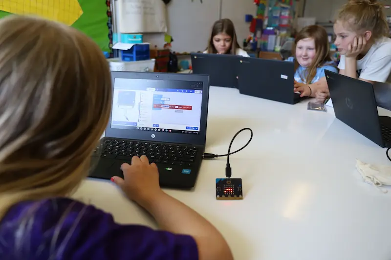 Student using blocks of code on a laptop to program a micro:bit.